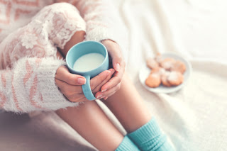 Girl on bed with long socks, mug of coffee and biscuits