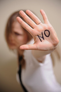 Woman holding up hand with NO written on her palm