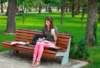 Girl writing in diary on park bench