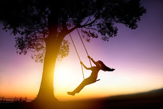 Woman on swing in sunset