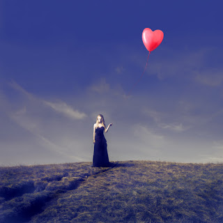 Woman in field with heart-shaped balloon