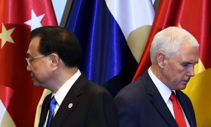 U.S. Vice President Mike Pence (R) and Chinese Premier Li Keqiang leave the stage after posing for a group photo before the start of the 13th East Asia summit plenary session on the sidelines of the 33rd Association of Southeast Asian Nations (ASEAN) summit in Singapore on Nov. 15, 2018. (ROSLAN RAHMAN/AFP/Getty Images)