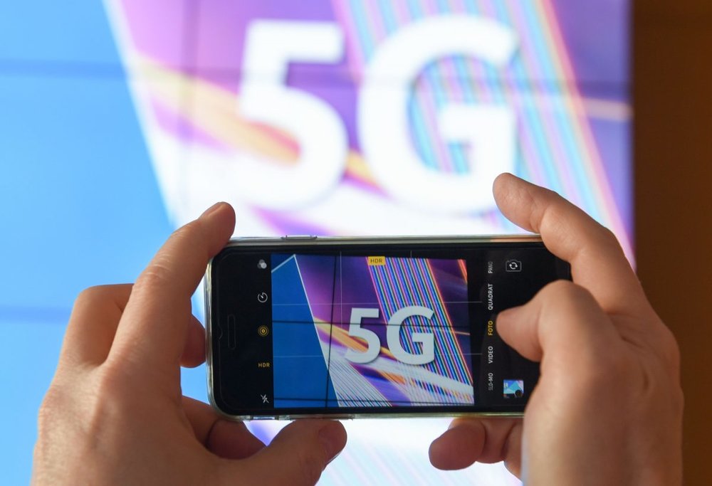 A journalist takes pictures of a projection screen prior to the start of Germany’s auction for the construction of an ultra-fast 5G mobile network on March 19, 2019 at the German Federal Network Agency in Mainz, western Germany. (Arne Dedert/AFP/Getty Images)