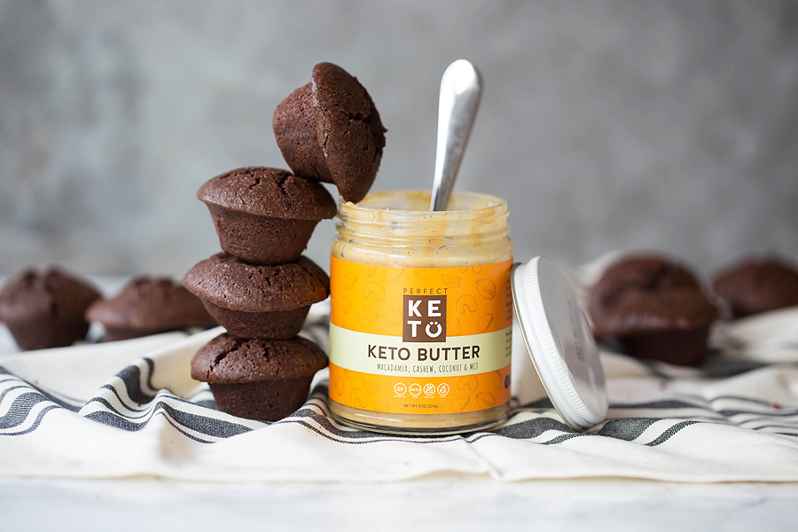 Perfect Keto Keto Butter next to a stack of four chocolate muffins