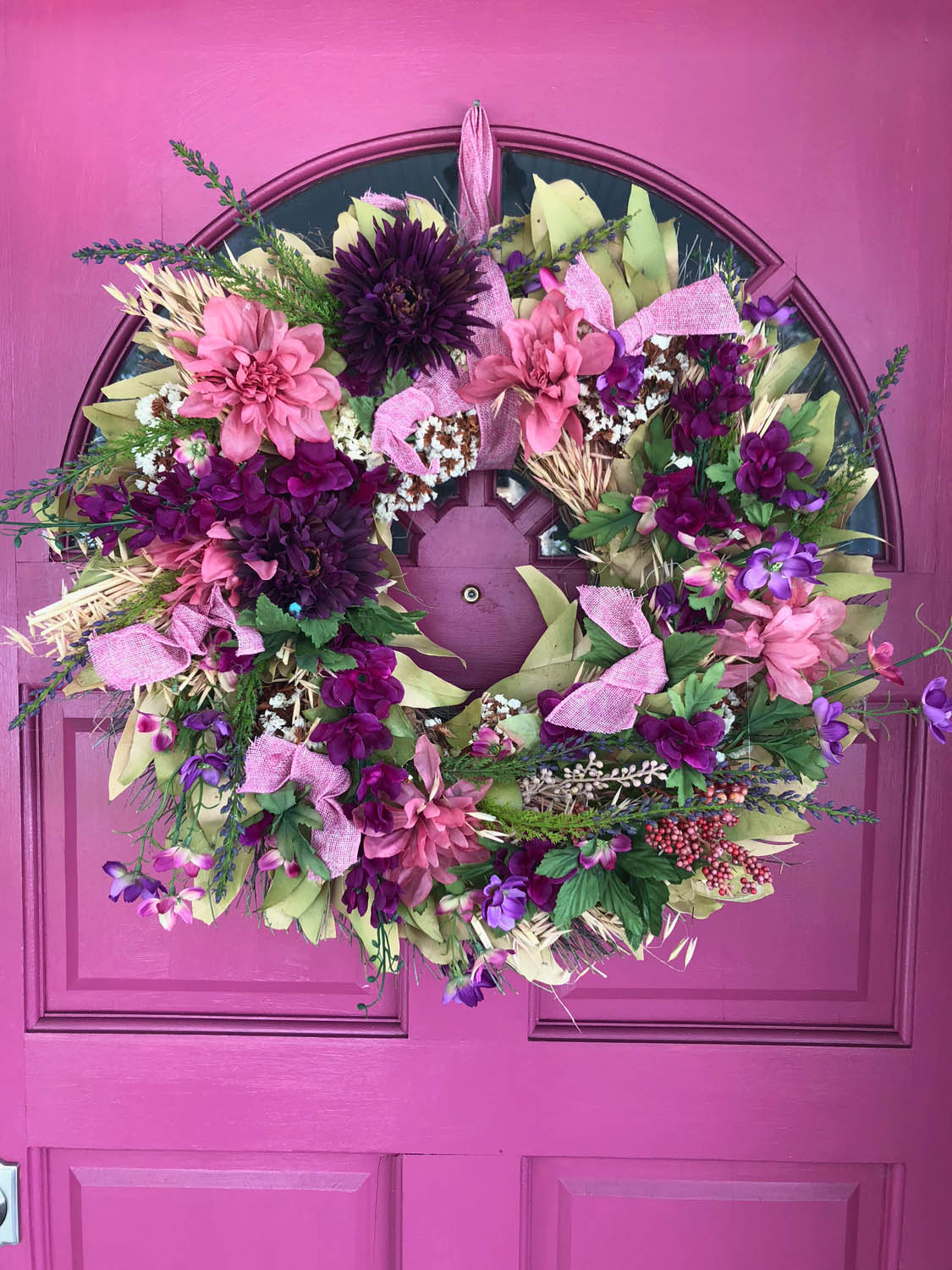 DIY spring wreath upcycle redo with fresh silk flowers hung on an exterior pink door