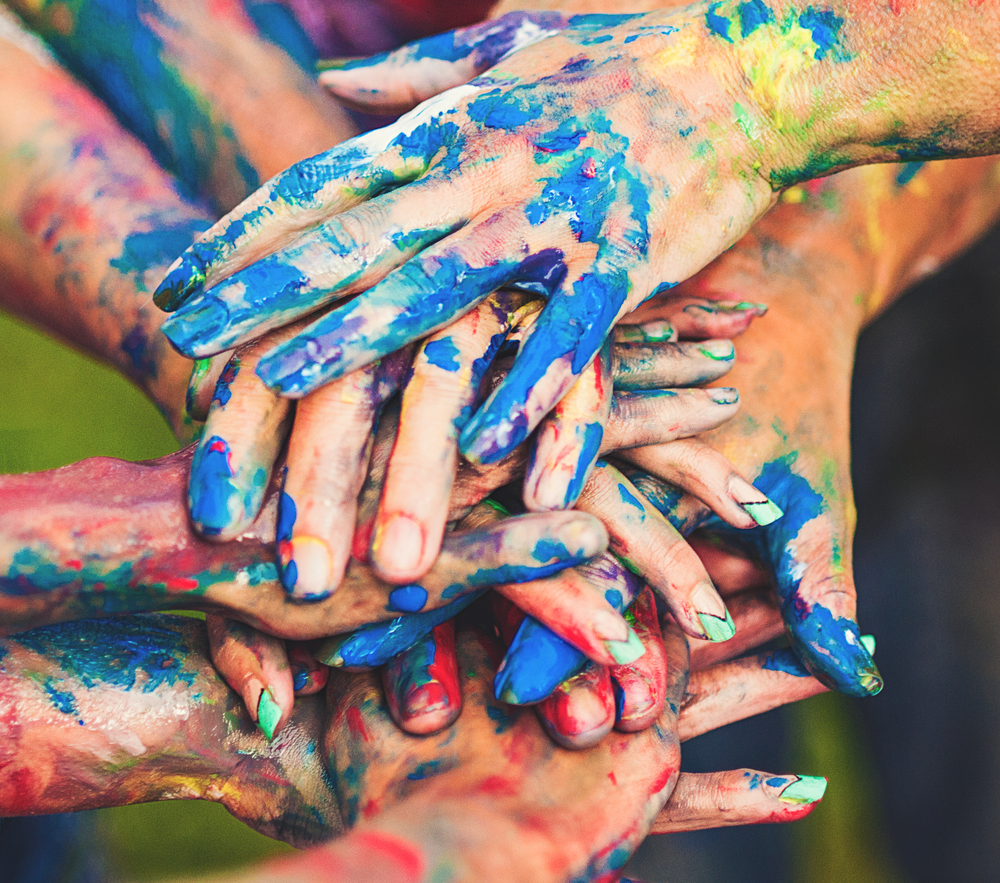 Paint covered hands join together after a team building event