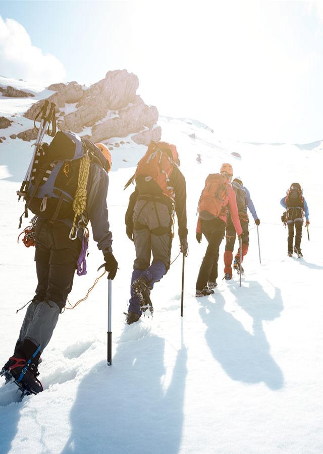 Climbers, tethered together by a single rope, ascend a snowy incline.
