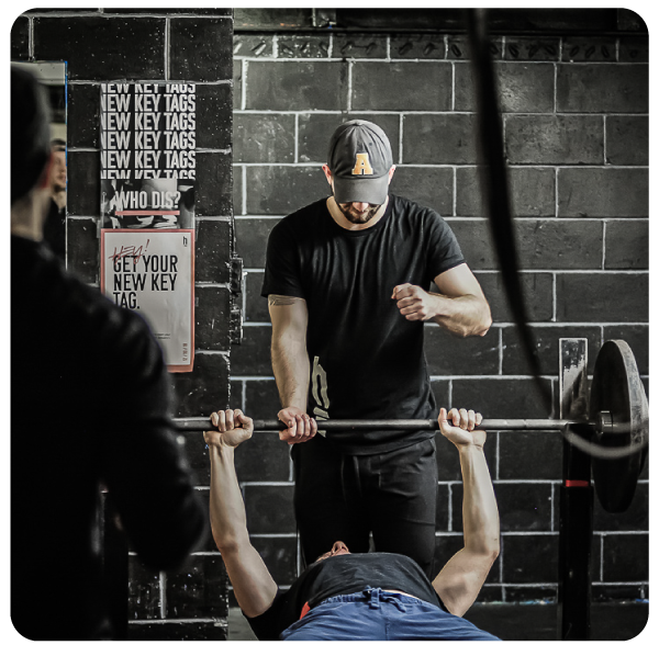 Trainer spotting client lifting weight over their head