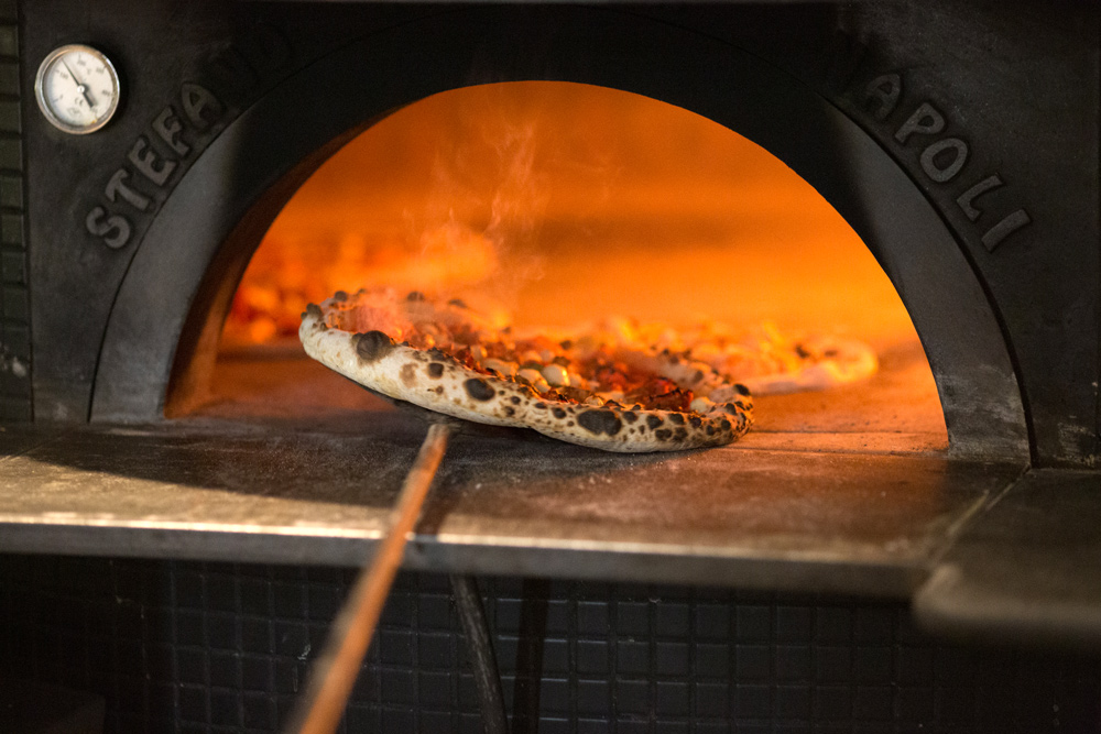 Woodfired pizza coming out of a pizza oven, with leoparding and bubbling cheese, in PI Pizza, Dublin 2 