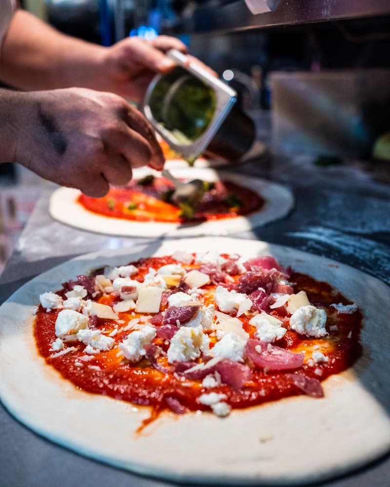Pi Pizza Dublin, toppings being placed on pizzas, for takeaway orders, or lunch or dinner service in the restaurant