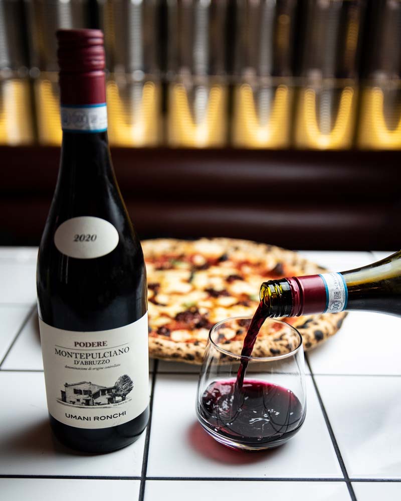 Pi Pizza Dublin, wine being poured with a Woodfired Pizza in the background, available for takeaway