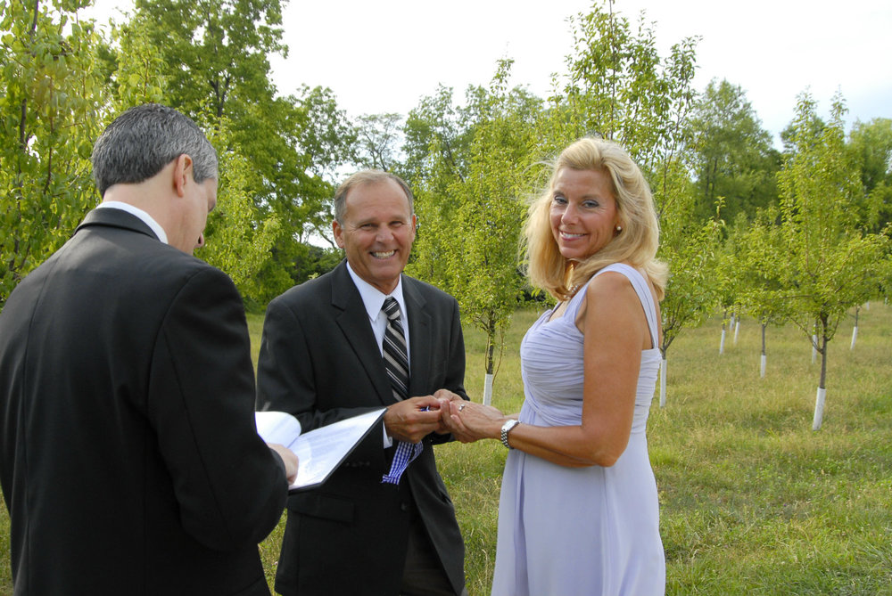 Bride and groom laugh with wedding officiant near Columbus Ohio