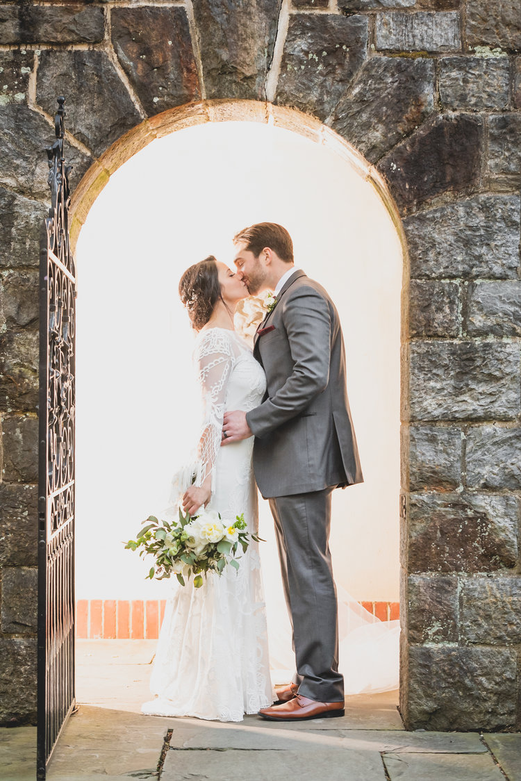 A Bride And Groom Kissing In The Stone Doorway Of An 19Th Century Cathedral.