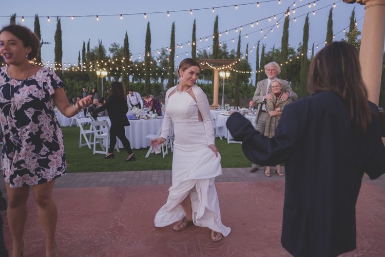 Ways To Keep Guests Cool At Your Warm-Weather Wedding - Bride At Her Outdoor Reception Dancing Solo Under A Darkening Sky.