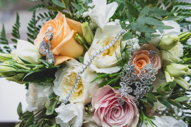 A Bouquet Of Roses Adorned With The Brides Jewelry.