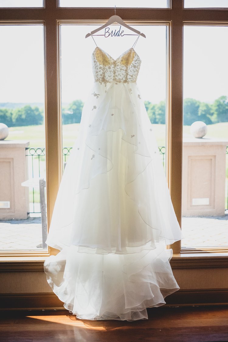 White Flowing Wedding Dress Hanging From A Window Sill In A Wooden Room.