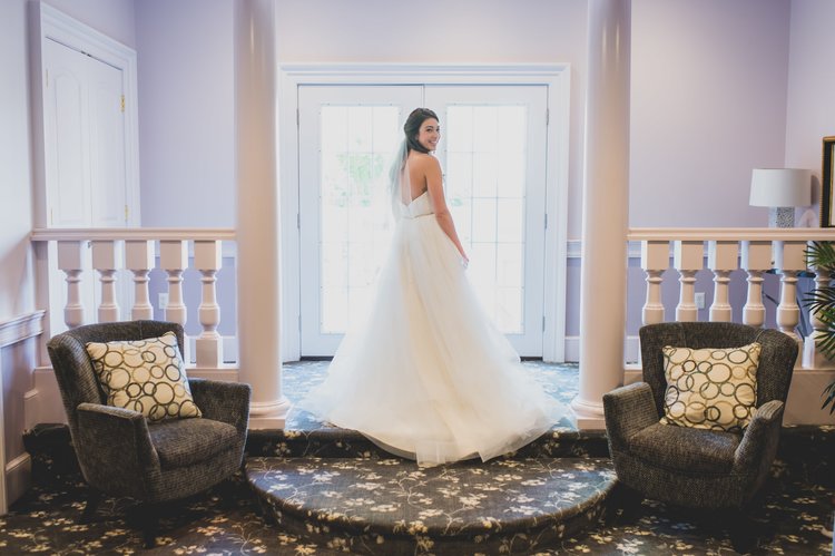 A Bride Showing Off Her Wedding Dress In A Purple Hued Room.