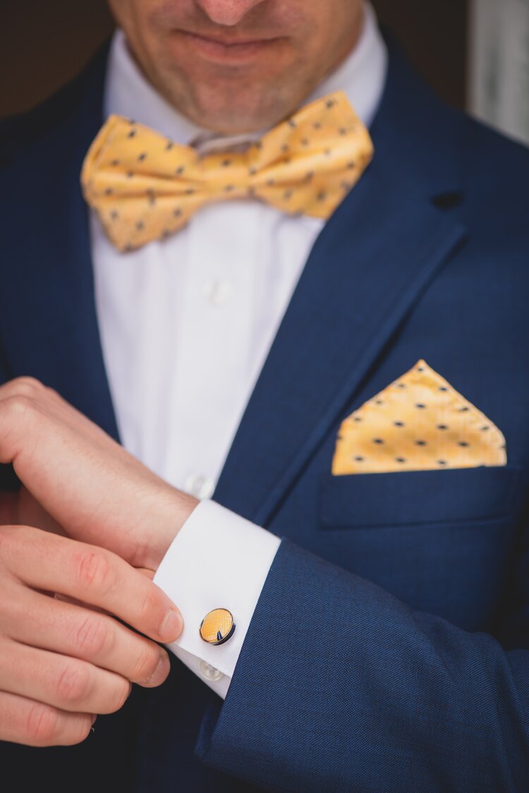Groom In A Navy Tuxedo Adjusting His Sleeve, Sporting Gold Cuff Links.