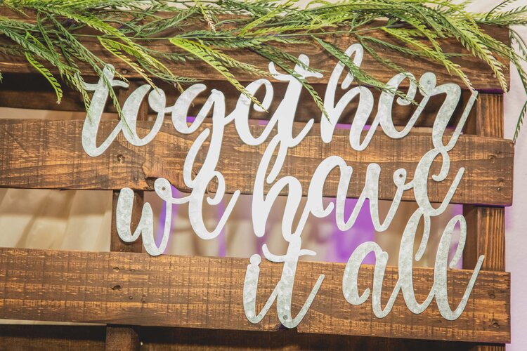 Cursive Letters On A Wooden Backdrop Reading “Together We Have It All.”