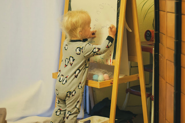 A toddler-age artist carefully draws a rendition of Cookie Monster on an IKEA easel. 