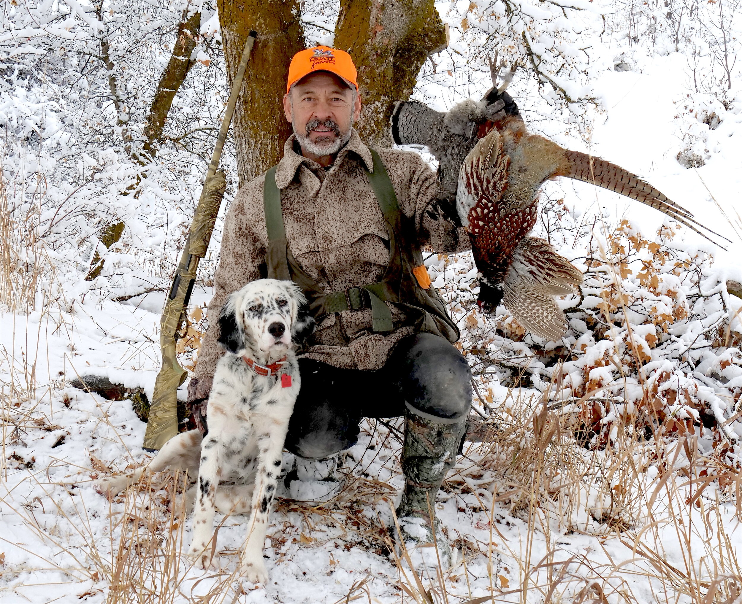 Image shows hunter and dog with a brace of upland game birds, pheasant and ruffed grouse, examples of sustainable conservation hunting