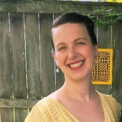 Headshot of Sophine stading in front of a fence in a backyard smiling