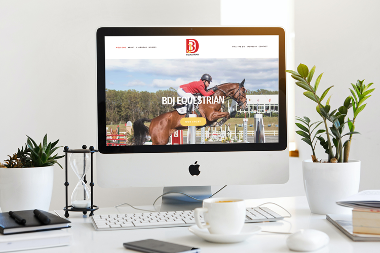 Photo of a desktop where the monitor displays the home page for bdj equestrian rider buck davidson jr jumping his horse over rails during a competition