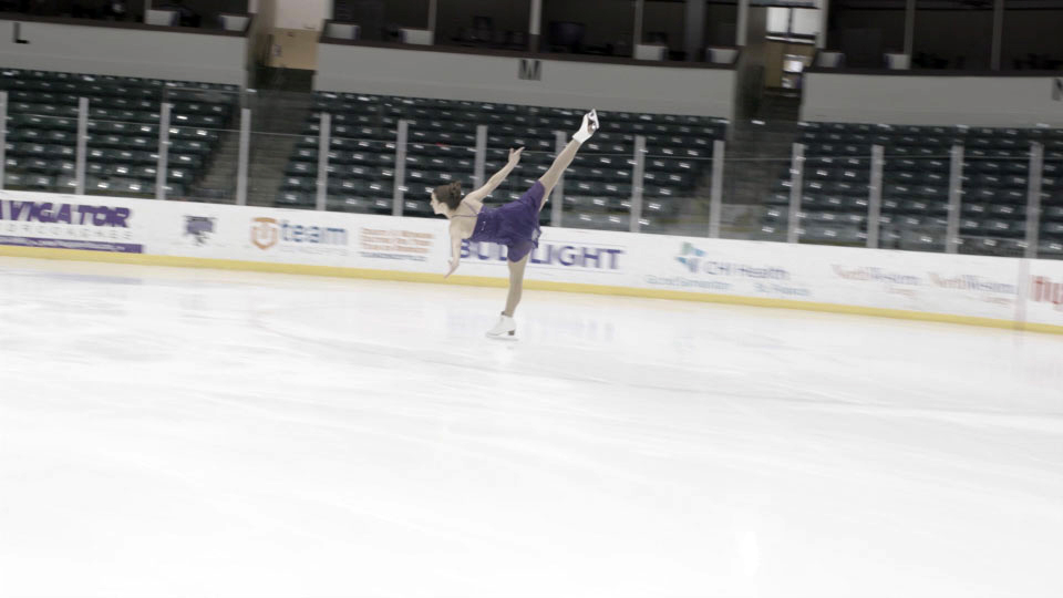 Ice skater in front of empty stands in a still from Ice the Movie