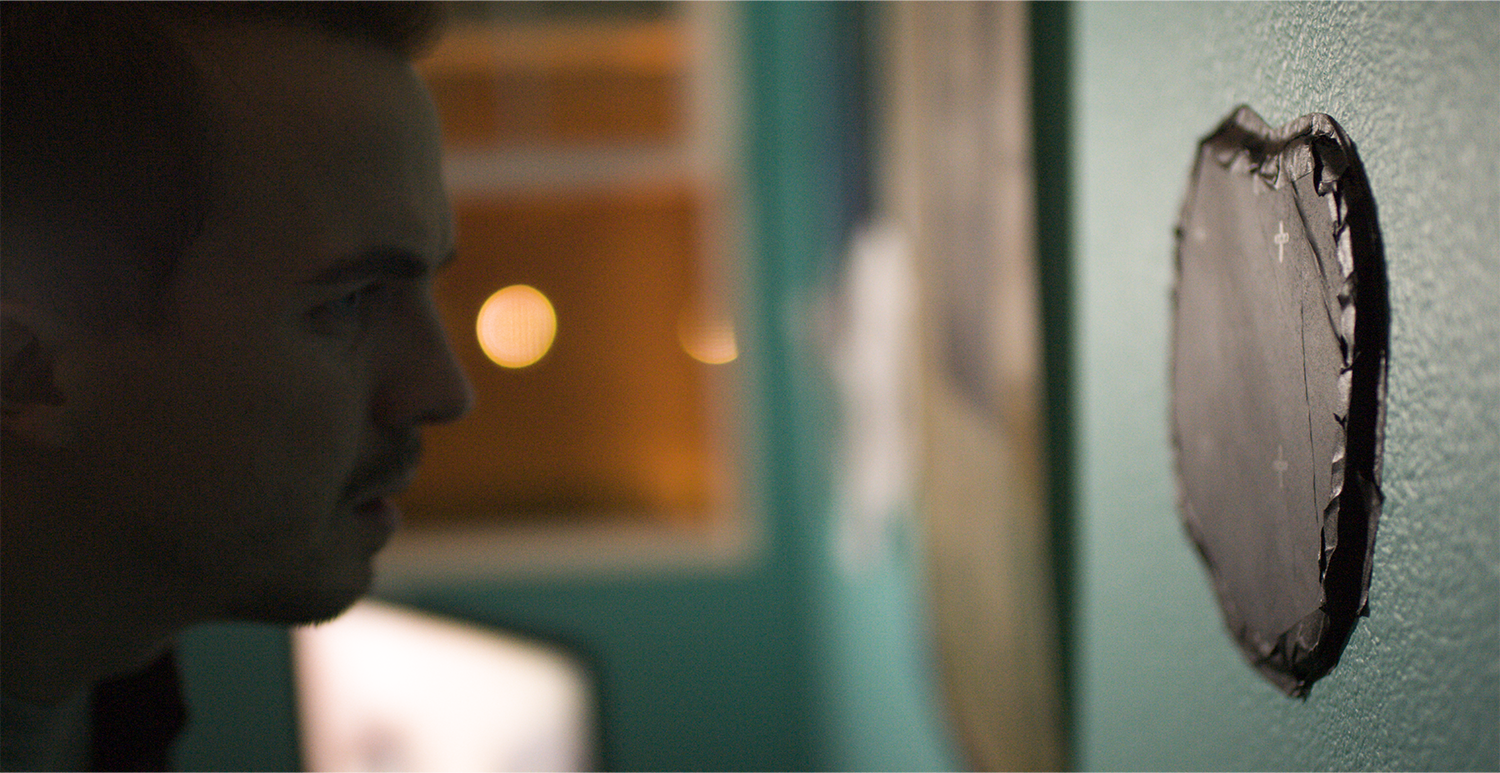 Actor Frankie Muniz stares at a black portal on a wall in the film The Black String