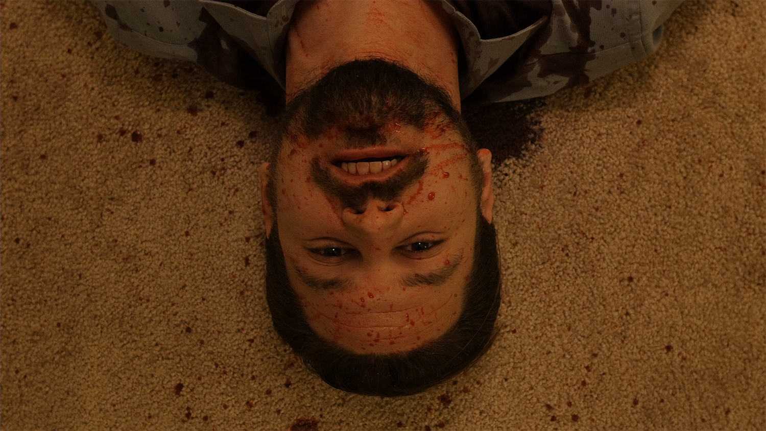 A bloodied actor lies on a carpeted floor in the movie Cruel Hearts