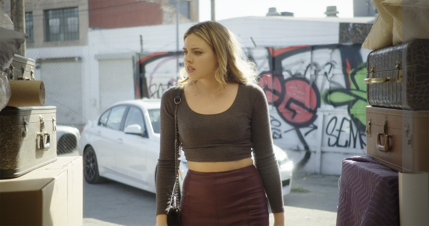 Actress enters a storage unit with graffiti behind her in an episode of Millennial Mafia