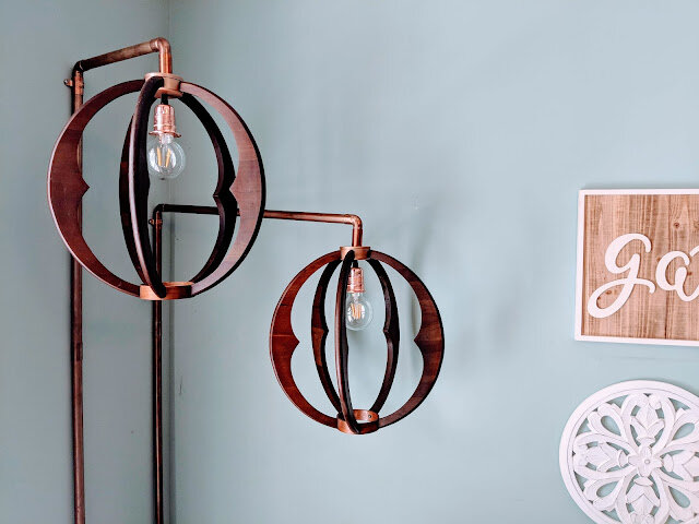 Copper and wood pendant lights with copper pipes attached to wall