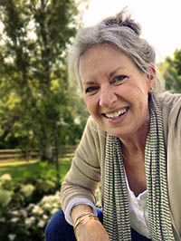 Leah Walker smiling outdoors with trees and garden in the background