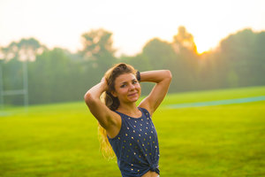 Woman during golden hour on a soccer field, with hands on her head