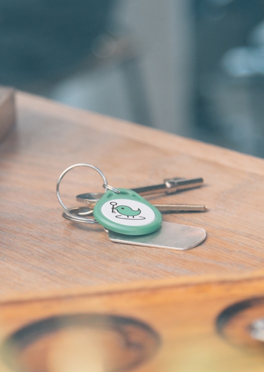 Green KeyNest fob and a set of metal keys on a table