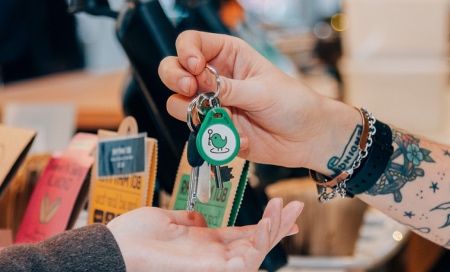 A person passing a key with a green KeyNest fob to someone’s hand