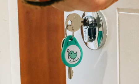A key inserted in the door lock, with a green KeyNest fob hanging from it