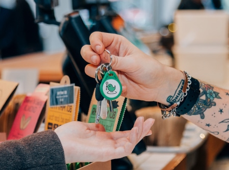 A person passing a key with a green KeyNest fob to someone’s hand