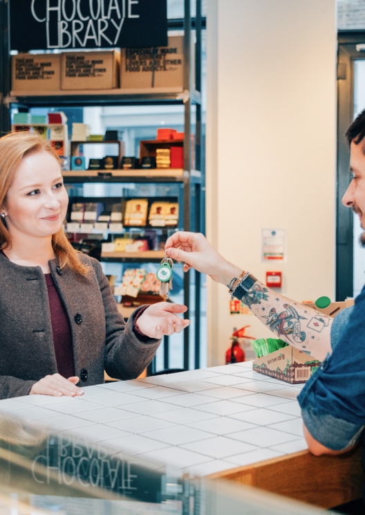 Shopkeeper passing keys to a customer over the counter