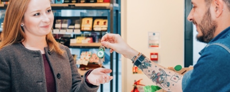 Shopkeeper passing keys to a customer over the counter