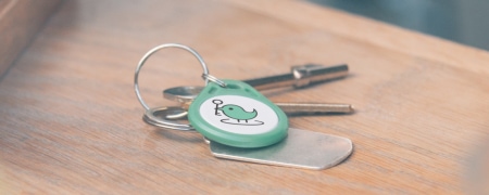 Green KeyNest fob and a set of metal keys on a table