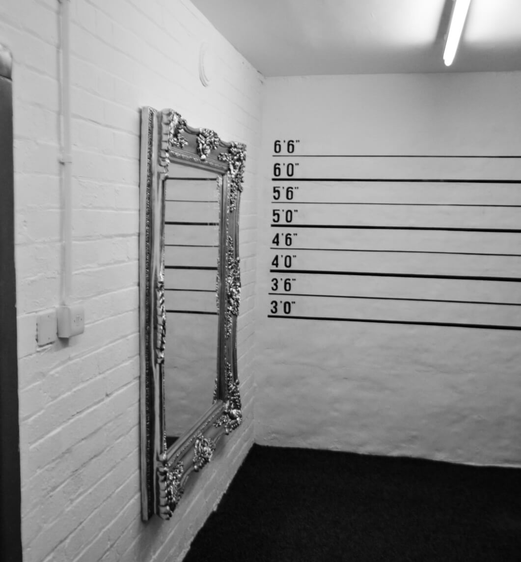 Interior of the store featuring a mirror and a wall painted as the background of an identity parade.