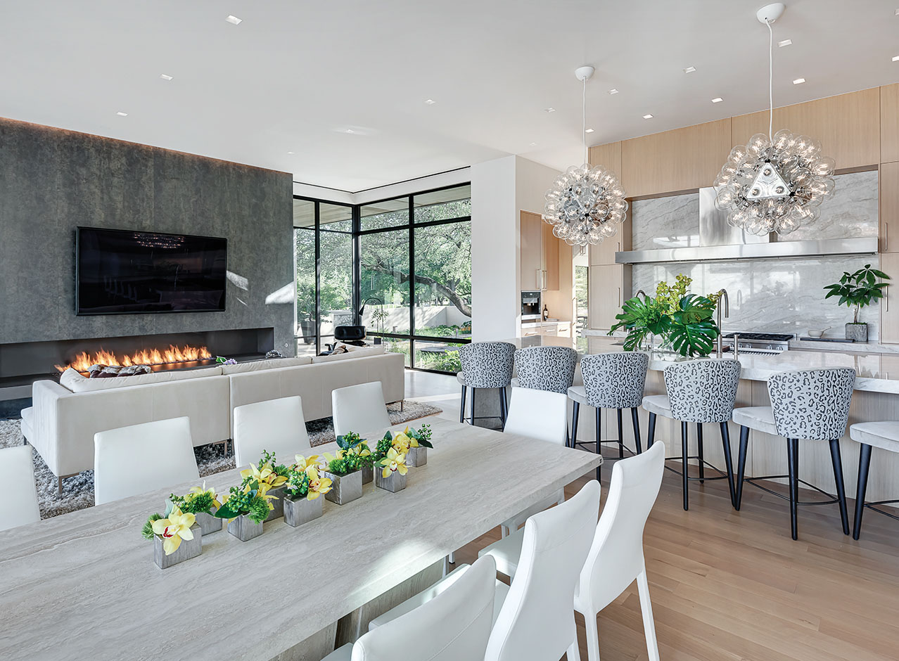 A Bernbaum/Magadini Architects comfortable modern contemporary living space in Preston Hollow Dallas Texas featuring a large, open living space with kitchen, fireplace and dining area.